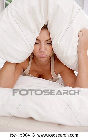 Young woman in bed with pillow on her head View Large Photo Image Stock Image - Young woman in bed with pillow on her head. Fotosearch