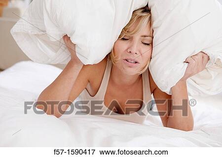 Young woman in bed with pillow on her head View Large Photo Image Stock Photo - Young woman in bed with pillow on her head. Fotosearch