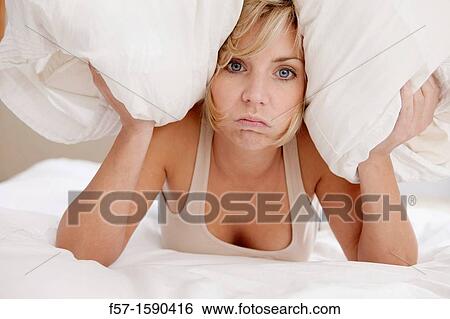 Young woman in bed with pillow on her head View Large Photo Image Stock Photograph - Young woman in bed with pillow on her head. Fotosearch