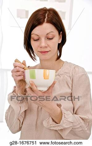 young woman in beige, holding a bowl in one hand and stirring with a spoon with the other hand View Large Photo Image Stock Image - young woman in beige, holding a bowl in one hand and stirring with a spoon with the other hand. Fotosearch