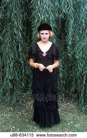 Stock Photography - Young woman in black standing in front of willow trees.. Fotosearch
