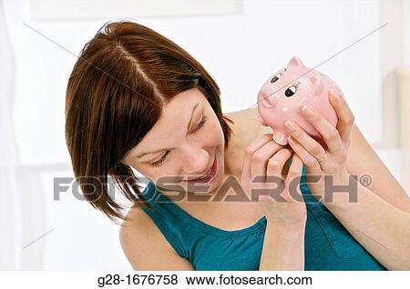 Young woman in blue holding a pink piggy money box View Large Photo Image Stock Photo - Young woman in blue holding a pink piggy money box. Fotosearch