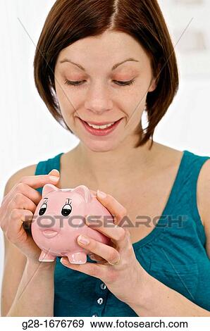 Young woman in blue holding a pink piggy money box View Large Photo Image Stock Photo - Young woman in blue holding a pink piggy money box. Fotosearch