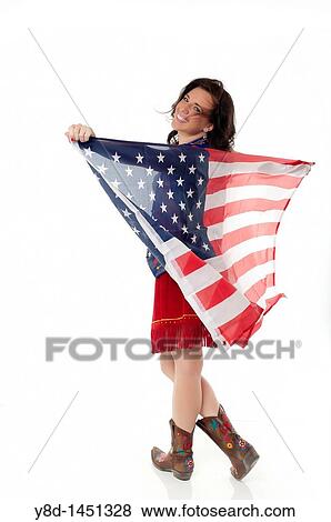 Stock Photo - Young woman in cowgirl outfit waving american flag. Fotosearch