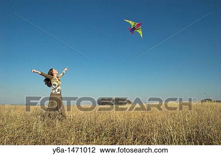 Young woman in field flying kite View Large Photo Image Stock Image - Young woman in field flying kite. Fotosearch