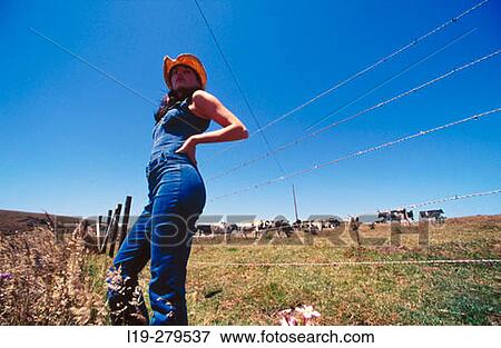 Stock Photo - young woman in field wearing cowboy hat. Fotosearch