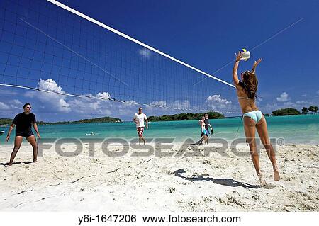 Stock Photograph - Young woman in green bikini jumping playing beach volleyball Chaweng Beach Ko Samui island Thailand. Fotosearch