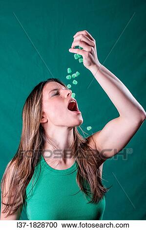 Young woman in green dropping green candy pieces in her mouth View Large Photo Image Stock Image - Young woman in green dropping green candy pieces in her mouth. Fotosearch