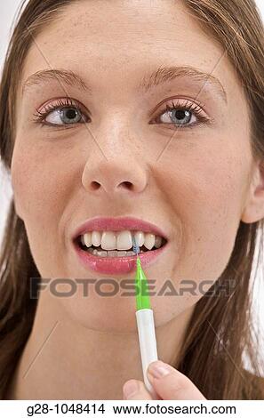 young woman in green top using an inter space tooth brush to clean her mouth in her bathroom View Large Photo Image Picture - young woman in green top using an inter space tooth brush to clean her mouth in her bathroom. Fotosearch