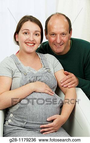 Young woman in grey, expecting a baby, with her father, both smiling and happy View Large Photo Image Stock Photograph - Young woman in grey, expecting a baby, with her father, both smiling and happy. Fotosearch