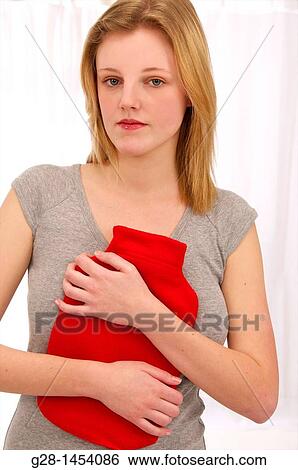 Young woman in grey holding a red hot water bottle on her painful stomach View Large Photo Image Stock Photograph - Young woman in grey holding a red hot water bottle on her painful stomach. Fotosearch