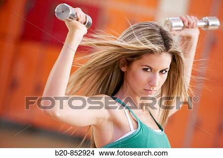 Young woman in gym doing exercise with dumbbells View Large Photo Image Picture - Young woman in gym doing exercise with dumbbells. Fotosearch