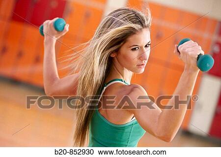 Young woman in gym doing exercise with dumbbells View Large Photo Image Stock Image - Young woman in gym doing exercise with dumbbells. Fotosearch