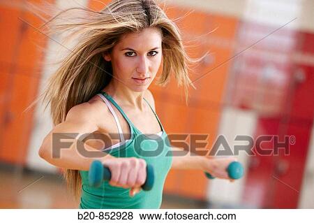 Young woman in gym doing exercise with dumbbells View Large Photo Image Stock Photo - Young woman in gym doing exercise with dumbbells. Fotosearch