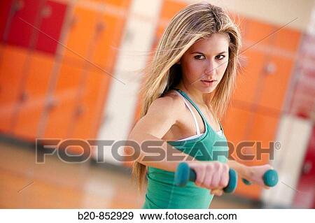 Young woman in gym doing exercise with dumbbells View Large Photo Image Stock Photo - Young woman in gym doing exercise with dumbbells. Fotosearch