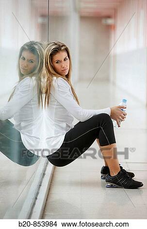 Young woman in gym resting and drinking water View Large Photo Image Picture - Young woman in gym resting and drinking water. Fotosearch