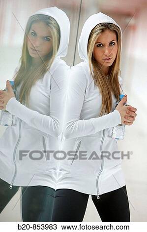 Stock Image - Young woman in gym resting and drinking water. Fotosearch