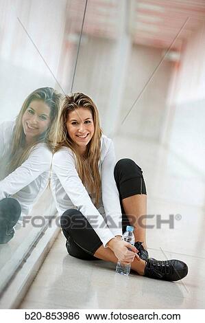 Young woman in gym resting and drinking water View Large Photo Image Stock Photograph - Young woman in gym resting and drinking water. Fotosearch