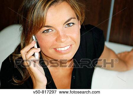 Young woman in her 30's speaking on a mobile phone, smiling, in an office in Cadiz, Spain White sofa and wooden walls View Large Photo Image Stock Photo - Young woman in her 30's speaking on a mobile phone, smiling, in an office in Cadiz, Spain White sofa and wooden walls. Fotosearch