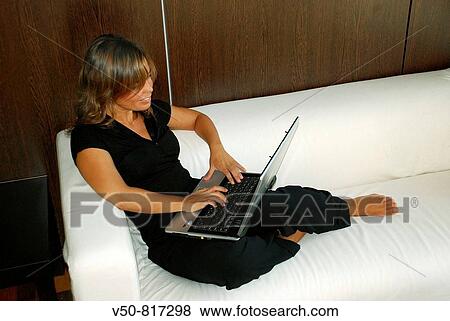 Young woman in her 30's working comfortably on her laptop, smiling, in an office in Cadiz, Spain White sofa and wooden walls View Large Photo Image Stock Photo - Young woman in her 30's working comfortably on her laptop, smiling, in an office in Cadiz, Spain White sofa and wooden walls. Fotosearch