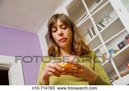 Young woman, in her kitchen, eating an orange. View Large Photo Image Stock Image - Young woman, in her kitchen, eating an orange.. Fotosearch