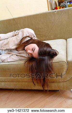 Stock Image - Young woman in jeans sleeping on sofa. Fotosearch