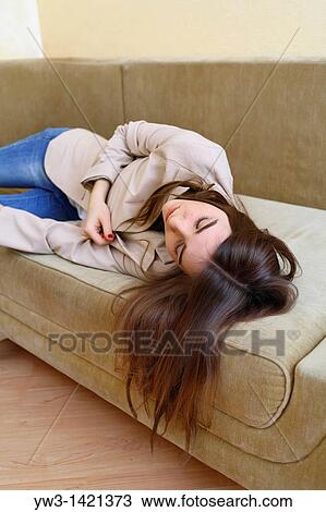 Stock Image - Young woman in jeans sleeping on sofa. Fotosearch