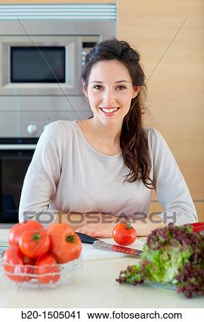 Stock Image - Young woman in kitchen. Fotosearch