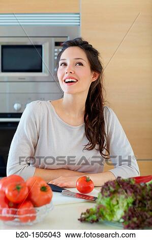Stock Image - Young woman in kitchen. Fotosearch