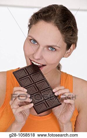 young woman in orange top, biting a tablet of black chocolate and smiling View Large Photo Image Stock Photo - young woman in orange top, biting a tablet of black chocolate and smiling. Fotosearch