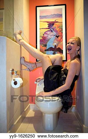 Stock Image - Young woman in party dress laughing in bathroom - South Florida, USA. Fotosearch