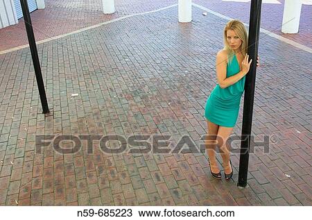 Stock Image - Young woman in party dress on street. Fotosearch