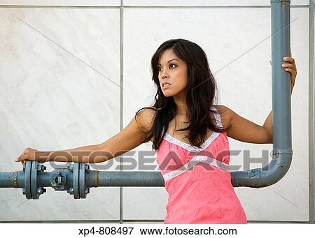 Young woman in pink dress leans against industrial piping. View Large Photo Image Stock Photo - Young woman in pink dress leans against industrial piping.. Fotosearch