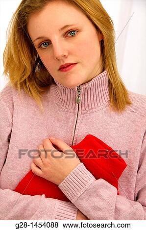 Young woman in pink holding a red hot water bottle on her painful stomach View Large Photo Image Stock Photo - Young woman in pink holding a red hot water bottle on her painful stomach. Fotosearch