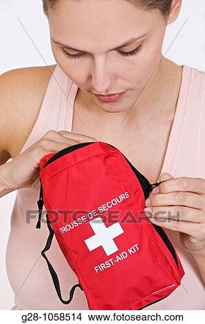 young woman in pink top holding a red first aid kit and looking for drugs in it View Large Photo Image Picture - young woman in pink top holding a red first aid kit and looking for drugs in it. Fotosearch