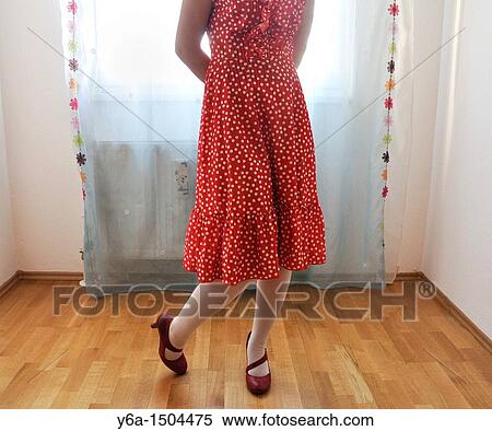 Stock Photography - Young woman in red dress standing indoors. Fotosearch