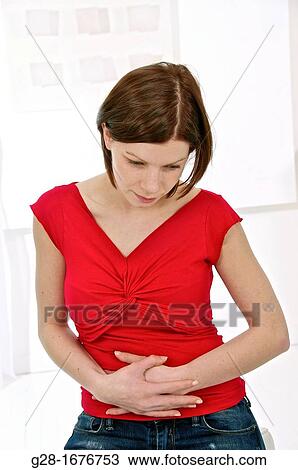 Young woman in red holding her stomach and feeling pains View Large Photo Image Stock Image - Young woman in red holding her stomach and feeling pains. Fotosearch