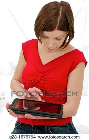 Young woman in red using her digital tablet View Large Photo Image Picture - Young woman in red using her digital tablet. Fotosearch