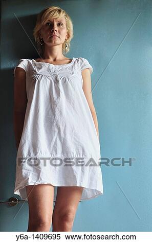 Stock Photography - Young woman in romantic white dress leaning against blue wall. Fotosearch