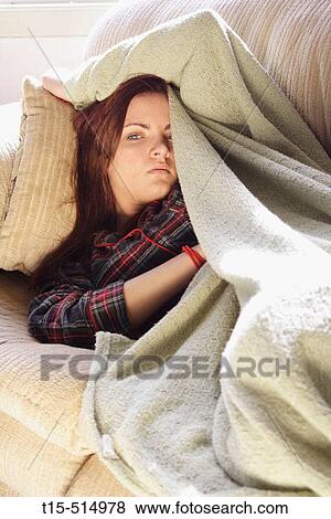 Stock Photo - Young woman in sofa in living room waking up. Fotosearch