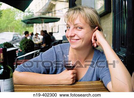 Stock Image - Young woman in street cafe with a glass of wine.. Fotosearch