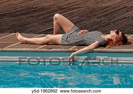 young woman in stripped dress resting, laying at poolside, hand touching the water View Large Photo Image Stock Image - young woman in stripped dress resting, laying at poolside, hand touching the water. Fotosearch
