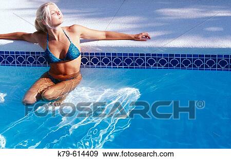 Stock Photo - Young woman in swimming pool enjoying the sun.. Fotosearch