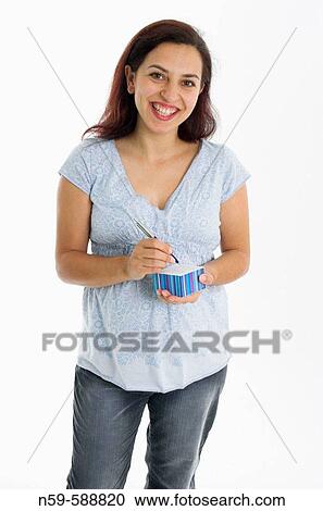 Stock Image - Young woman in the early stages of pregnancy writing notes.. Fotosearch