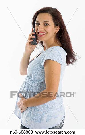 Stock Photo - Young woman in the early stages of pregnancy shares her exciting news on the telephone. Fotosearch