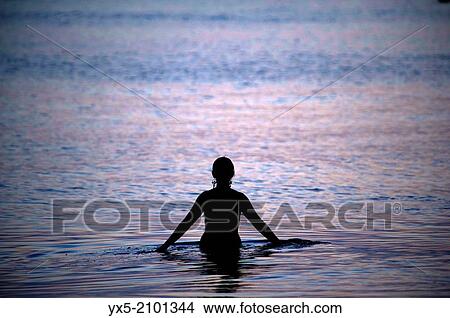 Young woman in the sea at dusk. View Large Photo Image Picture - Young woman in the sea at dusk.. Fotosearch
