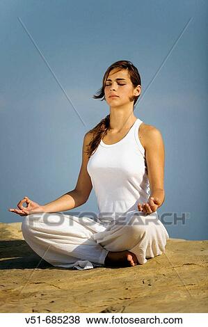 Young woman in white clothes doing yoga in a cliff View Large Photo Image Stock Photo - Young woman in white clothes doing yoga in a cliff. Fotosearch