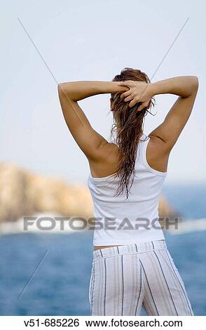 Stock Photograph - Young woman in white clothes looking at the sea. Fotosearch