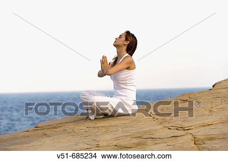 Young woman in white clothes soing Yoga in a cliff View Large Photo Image Picture - Young woman in white clothes soing Yoga in a cliff. Fotosearch