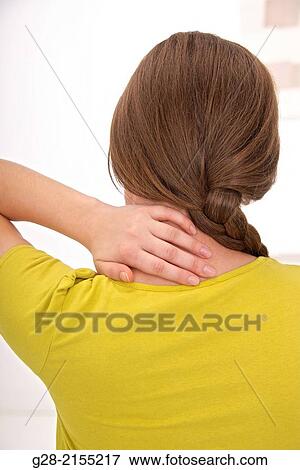 Young woman in yellow, seen from behind, suffering from neck and back, with her hand on the painful spot View Large Photo Image Stock Photo - Young woman in yellow, seen from behind, suffering from neck and back, with her hand on the painful spot. Fotosearch